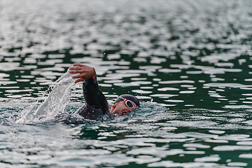 Image showing A professional triathlete trains with unwavering dedication for an upcoming competition at a lake, emanating a sense of athleticism and profound commitment to excellence.