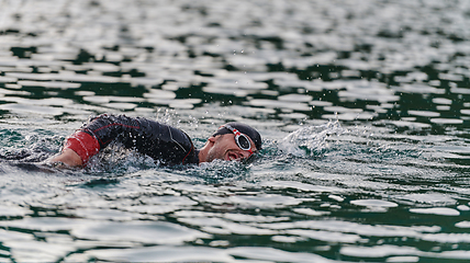 Image showing A professional triathlete trains with unwavering dedication for an upcoming competition at a lake, emanating a sense of athleticism and profound commitment to excellence.