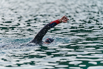 Image showing A professional triathlete trains with unwavering dedication for an upcoming competition at a lake, emanating a sense of athleticism and profound commitment to excellence.