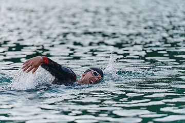 Image showing A professional triathlete trains with unwavering dedication for an upcoming competition at a lake, emanating a sense of athleticism and profound commitment to excellence.