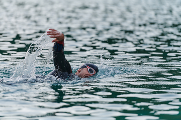 Image showing A professional triathlete trains with unwavering dedication for an upcoming competition at a lake, emanating a sense of athleticism and profound commitment to excellence.