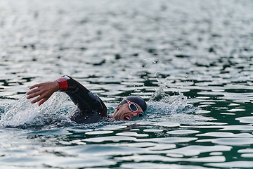 Image showing A professional triathlete trains with unwavering dedication for an upcoming competition at a lake, emanating a sense of athleticism and profound commitment to excellence.