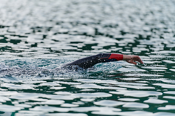 Image showing A professional triathlete trains with unwavering dedication for an upcoming competition at a lake, emanating a sense of athleticism and profound commitment to excellence.