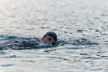 Image showing A professional triathlete trains with unwavering dedication for an upcoming competition at a lake, emanating a sense of athleticism and profound commitment to excellence.