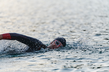 Image showing A professional triathlete trains with unwavering dedication for an upcoming competition at a lake, emanating a sense of athleticism and profound commitment to excellence.