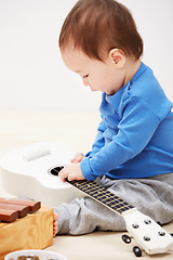 Image showing Baby, guitar toys and play in home for entertainment joy, childhood development or education. Boy, kid and instruments for musical strings for song learning in apartment or growing, progress or games