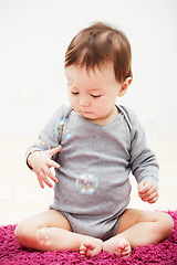 Image showing Baby, bubbles and playing game in home for childhood development, curious wondering or education. Kid, growth toys and mockup space or learning progress for sensory, coordination or entertainment