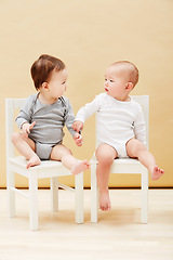 Image showing Kids, chair and baby boys for growth or child development in studio on an orange background. Youth, cute or adorable and sibling or little infant children sitting together for family bonding