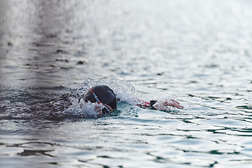 Image showing A professional triathlete trains with unwavering dedication for an upcoming competition at a lake, emanating a sense of athleticism and profound commitment to excellence.