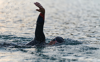 Image showing A professional triathlete trains with unwavering dedication for an upcoming competition at a lake, emanating a sense of athleticism and profound commitment to excellence.