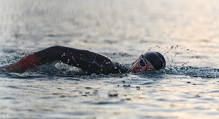 Image showing A professional triathlete trains with unwavering dedication for an upcoming competition at a lake, emanating a sense of athleticism and profound commitment to excellence.