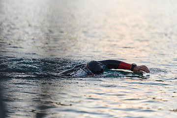 Image showing A professional triathlete trains with unwavering dedication for an upcoming competition at a lake, emanating a sense of athleticism and profound commitment to excellence.