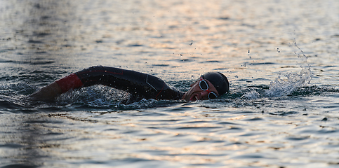 Image showing A professional triathlete trains with unwavering dedication for an upcoming competition at a lake, emanating a sense of athleticism and profound commitment to excellence.