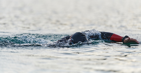 Image showing A professional triathlete trains with unwavering dedication for an upcoming competition at a lake, emanating a sense of athleticism and profound commitment to excellence.