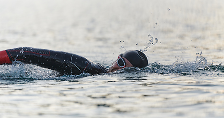 Image showing A professional triathlete trains with unwavering dedication for an upcoming competition at a lake, emanating a sense of athleticism and profound commitment to excellence.