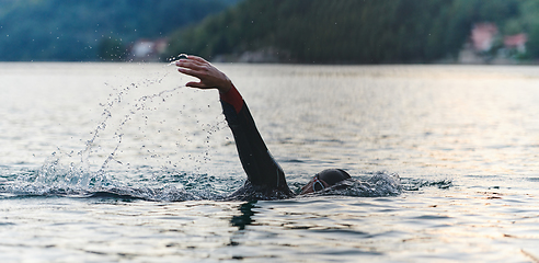 Image showing A professional triathlete trains with unwavering dedication for an upcoming competition at a lake, emanating a sense of athleticism and profound commitment to excellence.