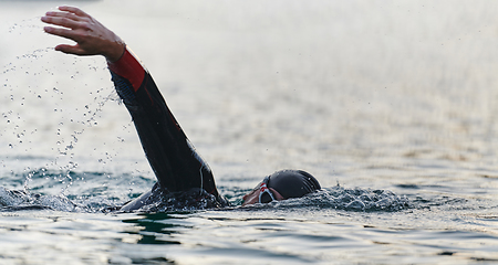 Image showing A professional triathlete trains with unwavering dedication for an upcoming competition at a lake, emanating a sense of athleticism and profound commitment to excellence.