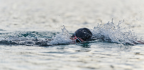 Image showing A professional triathlete trains with unwavering dedication for an upcoming competition at a lake, emanating a sense of athleticism and profound commitment to excellence.