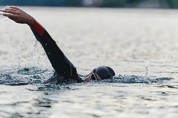 Image showing A professional triathlete trains with unwavering dedication for an upcoming competition at a lake, emanating a sense of athleticism and profound commitment to excellence.