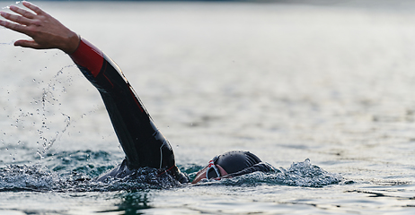 Image showing A professional triathlete trains with unwavering dedication for an upcoming competition at a lake, emanating a sense of athleticism and profound commitment to excellence.