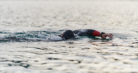 Image showing A professional triathlete trains with unwavering dedication for an upcoming competition at a lake, emanating a sense of athleticism and profound commitment to excellence.