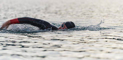 Image showing A professional triathlete trains with unwavering dedication for an upcoming competition at a lake, emanating a sense of athleticism and profound commitment to excellence.