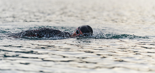 Image showing A professional triathlete trains with unwavering dedication for an upcoming competition at a lake, emanating a sense of athleticism and profound commitment to excellence.