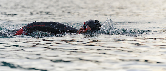 Image showing A professional triathlete trains with unwavering dedication for an upcoming competition at a lake, emanating a sense of athleticism and profound commitment to excellence.