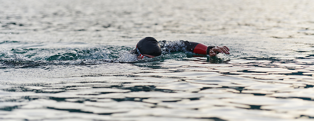 Image showing A professional triathlete trains with unwavering dedication for an upcoming competition at a lake, emanating a sense of athleticism and profound commitment to excellence.