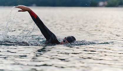 Image showing A professional triathlete trains with unwavering dedication for an upcoming competition at a lake, emanating a sense of athleticism and profound commitment to excellence.