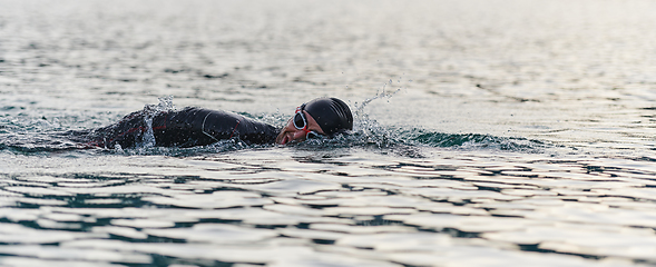 Image showing A professional triathlete trains with unwavering dedication for an upcoming competition at a lake, emanating a sense of athleticism and profound commitment to excellence.