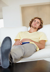 Image showing Bored man, remote control and watching tv on sofa with bad mood, chilling on streaming service in his home. Depression, lonely and sad male person in a living room with television, cable or movies