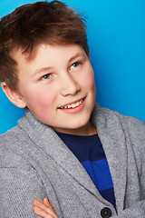 Image showing Fashion, thinking and boy child in studio with arms crossed confidence, smile or positive attitude on blue background. Style, face and proud fashionable kid model with cool, outfit or clothing choice