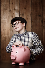 Image showing Piggy bank, money and boy child with savings, growth or investment, planning or learning at home. Happy, budget and kid in a house with coin, container or cash box for future, financial and security