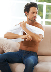 Image showing Take off, tshirt and man on sofa in a house for comfort, rest or chilling on weekend, day off or vacation. Sweater, removal or male person in living room undressing, relax and ready to be comfortable