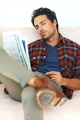 Image showing Man, relax and reading a newspaper on couch in home, living room and learning about event from media. Calm, weekend and person with news, paper or article on sofa in apartment with information