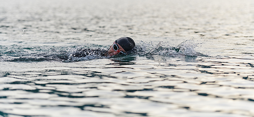 Image showing A professional triathlete trains with unwavering dedication for an upcoming competition at a lake, emanating a sense of athleticism and profound commitment to excellence.