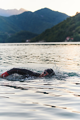 Image showing A professional triathlete trains with unwavering dedication for an upcoming competition at a lake, emanating a sense of athleticism and profound commitment to excellence.