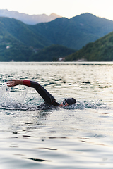 Image showing A professional triathlete trains with unwavering dedication for an upcoming competition at a lake, emanating a sense of athleticism and profound commitment to excellence.