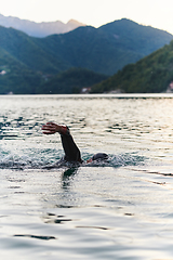 Image showing A professional triathlete trains with unwavering dedication for an upcoming competition at a lake, emanating a sense of athleticism and profound commitment to excellence.