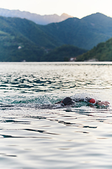 Image showing A professional triathlete trains with unwavering dedication for an upcoming competition at a lake, emanating a sense of athleticism and profound commitment to excellence.