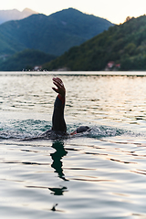 Image showing A professional triathlete trains with unwavering dedication for an upcoming competition at a lake, emanating a sense of athleticism and profound commitment to excellence.