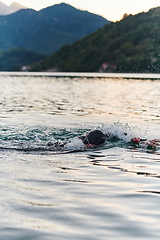 Image showing A professional triathlete trains with unwavering dedication for an upcoming competition at a lake, emanating a sense of athleticism and profound commitment to excellence.