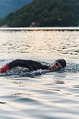 Image showing A professional triathlete trains with unwavering dedication for an upcoming competition at a lake, emanating a sense of athleticism and profound commitment to excellence.