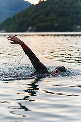 Image showing A professional triathlete trains with unwavering dedication for an upcoming competition at a lake, emanating a sense of athleticism and profound commitment to excellence.