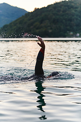 Image showing A professional triathlete trains with unwavering dedication for an upcoming competition at a lake, emanating a sense of athleticism and profound commitment to excellence.