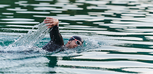 Image showing A professional triathlete trains with unwavering dedication for an upcoming competition at a lake, emanating a sense of athleticism and profound commitment to excellence.