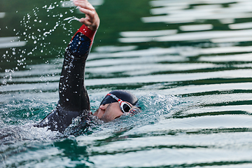 Image showing A professional triathlete trains with unwavering dedication for an upcoming competition at a lake, emanating a sense of athleticism and profound commitment to excellence.