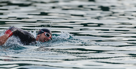 Image showing A professional triathlete trains with unwavering dedication for an upcoming competition at a lake, emanating a sense of athleticism and profound commitment to excellence.