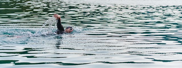 Image showing A professional triathlete trains with unwavering dedication for an upcoming competition at a lake, emanating a sense of athleticism and profound commitment to excellence.